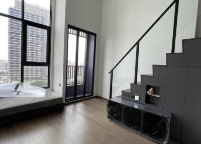 Spacious living room with high ceilings, large windows, and modern staircase