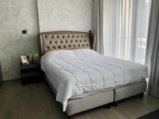 Elegant bedroom with a upholstered bed, nightstand, and large window