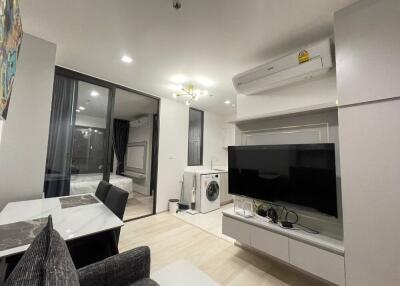 Modern living room with TV, washer, and access to bedroom