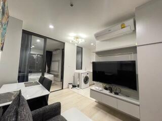 Modern living room with TV, washer, and access to bedroom