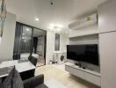 Modern living room with TV, washer, and access to bedroom