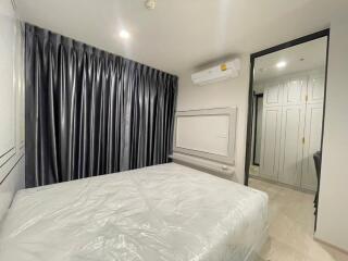 Bedroom with large bed, gray curtains, and air conditioning unit