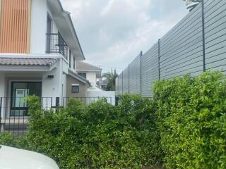 Modern two-story house with lush green hedge and fencing