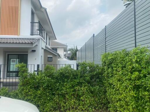 Modern two-story house with lush green hedge and fencing