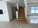 Staircase leading to upper floor with tiled flooring and large window