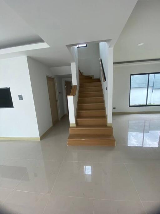 Staircase leading to upper floor with tiled flooring and large window