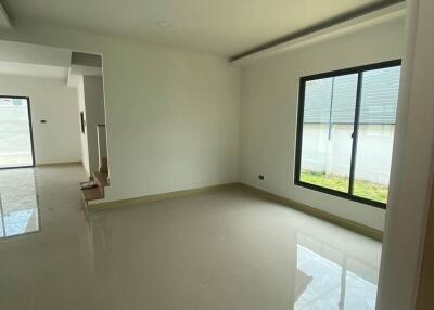 Spacious empty living area with large window and tile flooring