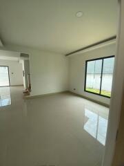 Spacious empty living area with large window and tile flooring