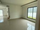 Spacious empty living area with large window and tile flooring