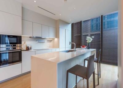 Modern kitchen with island, stools, appliances, and large windows