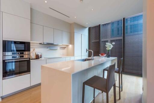 Modern kitchen with island, stools, appliances, and large windows