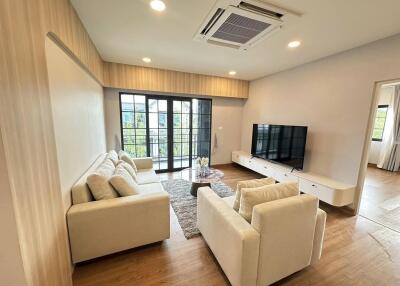 Modern furnished living room with sofa, TV, and large windows