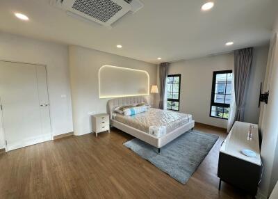 Spacious modern bedroom with hardwood floors and cozy bed