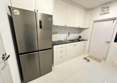 Modern kitchen with stainless steel refrigerator and white cabinets