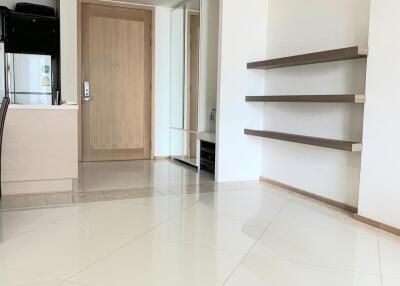 Bright living room with tiled floor, shelves, and a view of the entrance