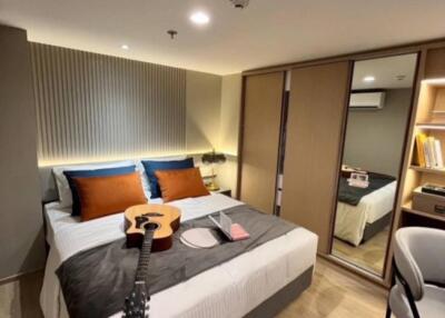 Modern bedroom with double bed, guitar, and wardrobe