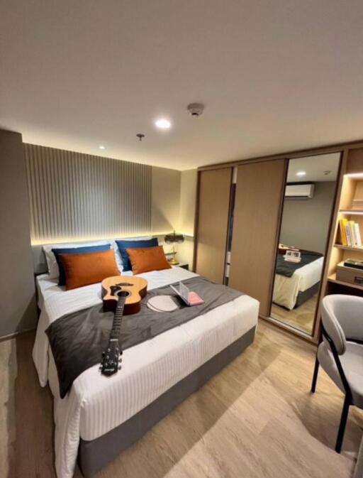 Modern bedroom with double bed, guitar, and wardrobe