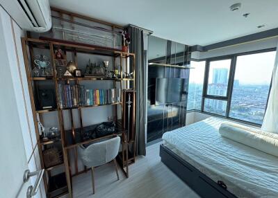 Modern bedroom with bookshelves, desk, and city view