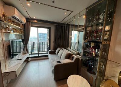 Modern living room with a large sofa, TV, glass cabinet and wall-to-wall windows with a city view