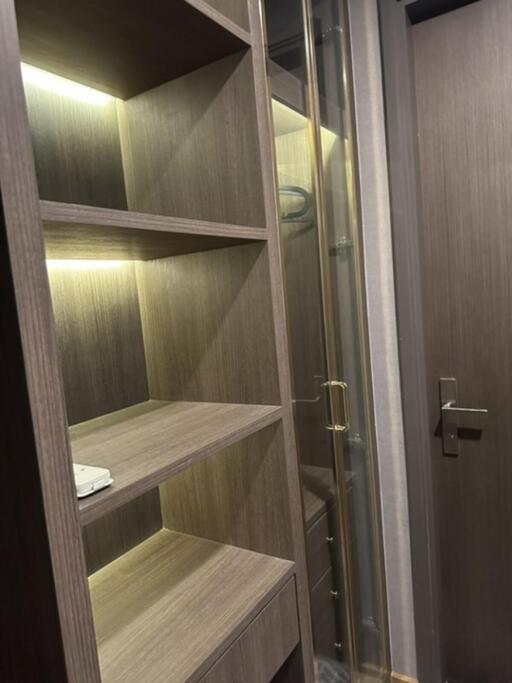 Modern walk-in closet with built-in wooden shelving and soft lighting