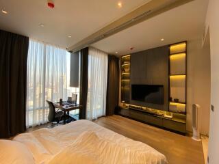 Modern bedroom with large windows, desk, and built-in entertainment unit