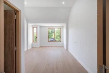 Empty living room with large windows and wooden flooring