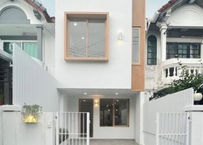 Front view of a modern, white, two-story house with a gated driveway