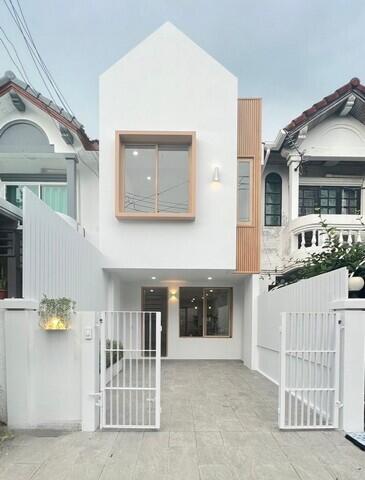 Front view of a modern, white, two-story house with a gated driveway