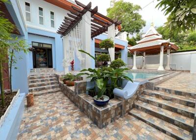 Outdoor pool area with tiled flooring, stairs, and pavilion