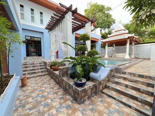 Outdoor pool area with tiled flooring, stairs, and pavilion