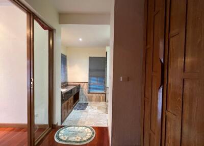 View of a partially open bathroom with wooden cabinets and marble flooring.