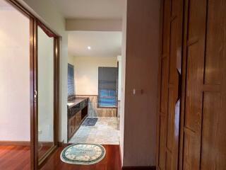 View of a partially open bathroom with wooden cabinets and marble flooring.