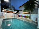 Outdoor view of a swimming pool at dusk, with a gazebo and surrounding decorations.