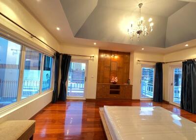 Spacious bedroom with wooden flooring, large windows, and a chandelier