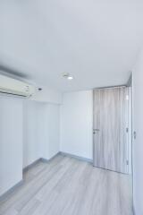 A minimalist bedroom with hardwood flooring and air conditioning