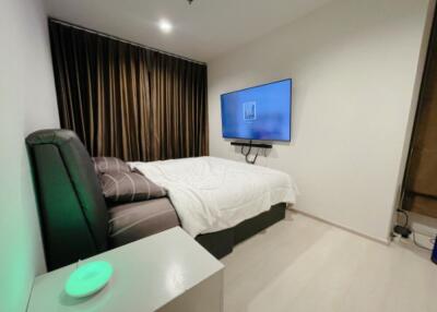 Modern bedroom with a TV mounted on the wall, a large bed, and dark curtains.