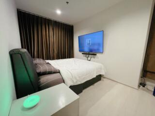 Modern bedroom with a TV mounted on the wall, a large bed, and dark curtains.