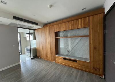 Modern living area with wooden built-in storage and view into the kitchen