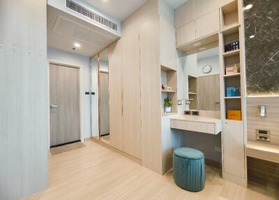 Bedroom with built-in storage, vanity area, and a door leading to the next room