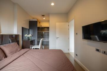 Modern bedroom with a desk area and wall-mounted TV