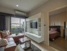 Modern living room with leather couch and wall-mounted TV unit adjacent to a bedroom