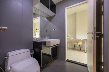 Modern bathroom with mirrored cabinets and a view into adjoining room