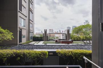 Exterior view of a modern building with outdoor seating area and city skyline in the background