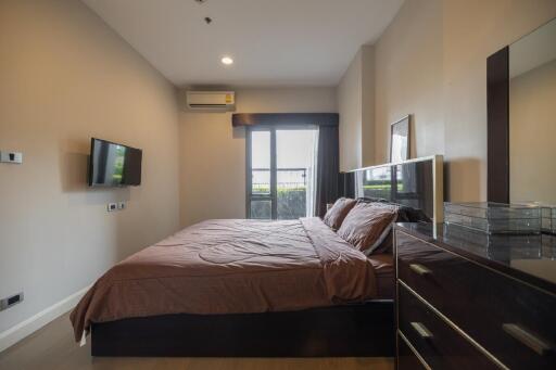 Bedroom with a large bed, wall-mounted TV, and a dresser