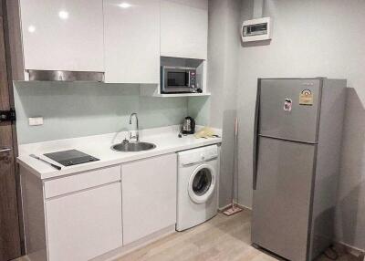 Modern kitchen with white cabinets, sink, microwave, and refrigerator