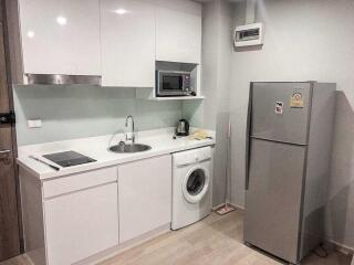 Modern kitchen with white cabinets, sink, microwave, and refrigerator