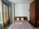 Bedroom with large window and wooden furniture