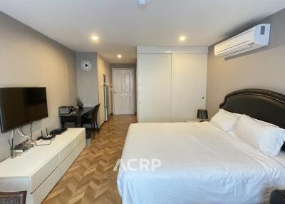 Spacious bedroom with bed, wall-mounted TV, and air conditioning