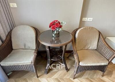 Cozy sitting area with two wicker chairs and a round table with a flower vase