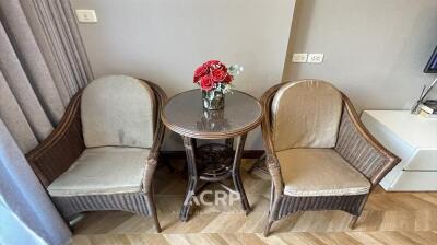 Cozy sitting area with two wicker chairs and a round table with a flower vase